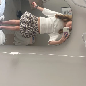 Leopardmönstrad kortkjol från Kappahl - Säljer en fluffig och voluminös kortkjol från Kappahl med snyggt leopardmönster i beige och svart. Kjolen har bred resår i midjan och är perfekt för dig som vill sticka ut med en trendig look. Superenkel att matcha med både sneakers och boots.