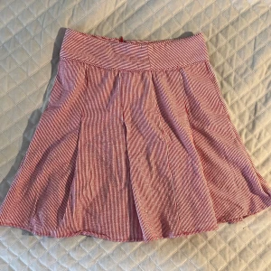 Rödvit randig kjol från FRN - Superfin kort kjol från FRN by Fame i rödvitt randigt mönster. Kjolen har bred midja, lätt utställd form och dragkedja bak. Tillverkad i mjuk bomull med lite stretch för extra komfort. Perfekt för dig som gillar en lekfull och fräsch stil!💗