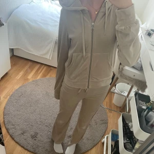 Mjukisset - Ginatricot - Säljer ett set från gina med en beige hoodie i mjuk velour med huva och snörning. Tröjan har dragkedja framtill med en rund metallring, samt två fickor. Och sedan matchande mjukisbyxor till! Tröjan i XS, byxor i XXS