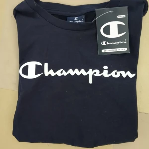Mörkblå Champion t-shirt, storlek 138/142 - Mörkblå t-shirt från Champion med stor vit logga, barnstorlek M (138/142), helt ny, tagg kvar.