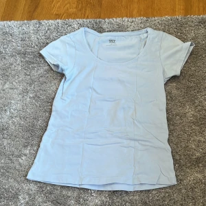 Ljusblå t-shirt - Säljer en ljusblå t-shirt från Lager 157 i mjuk bomullsblandning. T-shirten har rund halsringning och korta ärmar, perfekt för en enkel och stilren look.