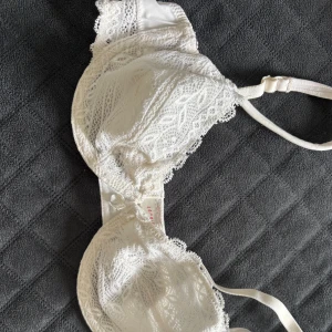 Vit spets-bh från Esprit - Säljer en vit bh från Esprit med vacker spets och dekorativ rosett framtill. Bh:n har justerbara axelband och fina spetsdetaljer över hela kuporna. 