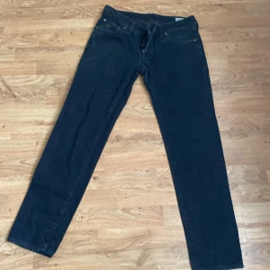 Svarta jeansbyxor från G-Star - Säljer ett par svarta jeansbyxor från G-Star med raka ben och klassisk femficksdesign. Byxorna har knäppning med knappar och diskret G-Star-logga på bakfickan. Perfekta för dig som gillar en enkel och stilren look.
