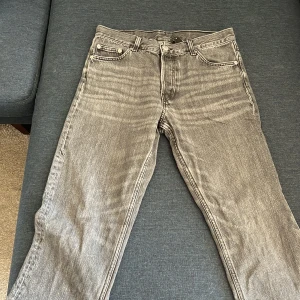 Grå/Svarta jeansbyxor från Weekday - Säljer ett par grå/svarta jeansbyxor från Weekday i modellen Barrel. Byxorna har fem fickor, normal passform och raka ben. Klassisk knappgylf och bälteshällor. Perfekta för dig som gillar en enkel och stilren look.