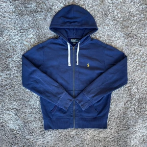 Ralph Lauren Marinblå Zip Hoodie - Säljer denna  Ralph Lauren Zip hoodie | Tröjan har inga synliga skador vid användning men om man tittar noga finns det ett litet hål på vardera arm | Strl: S | Färg: Mörkblå | Hör av dig vid minsta fundering :)