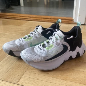 IMMORTALITY BASKETBOLLSKOR.  - Säljer ett par snygga Nike basketskor i vitt och svart med mintgröna detaljer och vit sula. Skorna har en sportig design med meshmaterial och stora swoosh-loggor på sidorna. Basketskor. Bekväma. 