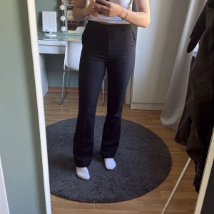 Svarta kostymbyxor från BikBok - Snygga svarta kostymbyxor från BikBok med hög midja och bootcut. Byxorna har diskreta fickor i sidorna och stängs med dragkedja och knapp. Perfekta för en stilren look. Dom är i modellen Wilma Tall, jag är 179cm med långa ben💕