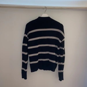 Svart och grå randig stickad tröja från VILA - Säljer en svart stickad tröja från VILA med gråa tjocka ränder. Tröjan har lång ärm och är i mjukt stickat material, perfekt för kyligare dagar. Klassisk passform och enkel att matcha med olika outfits.