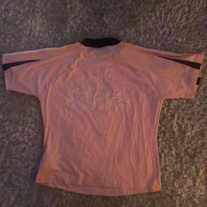 Rosa t-shirt från Adidas med svarta detaljer - Rosa t-shirt från Adidas med svarta och vita detaljer på axlar och ärmar.