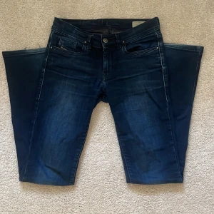 Mörkblå bootcut jeans från Diesel - Säljer ett par mörkblå jeans från Diesel med klassisk femficksdesign och lätt slitning. Jeansen har bootcut-passform och låg midja. De har en liten defekt längst ner som ni ser på första bilden men skriv för fler bilder eller andra frågor🩷