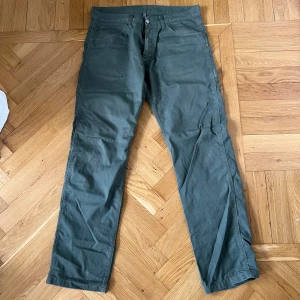 Gröna cargopants från Carhartt - Säljer ett par gröna cargopants från Carhartt med raka ben och flera praktiska fickor. Byxorna har normal passform och klassisk cargostil, perfekta för en avslappnad look. Stängs med dragkedja och knapp framtill.
