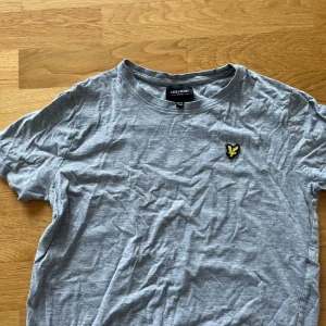 Grå Lyle&Scott T-shirt  - Hej jag säljer min gråa Lyle&Scott T-shirt som jag växt ut ur. På bilden är den skrynklig men går absolut att stryka för en raka passform!