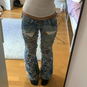 Unika jeans - Snygga jeans med massa hål i för en unik look. Midja: 37 innerben:83 cm. Dom är lågmidjade och bootcut.