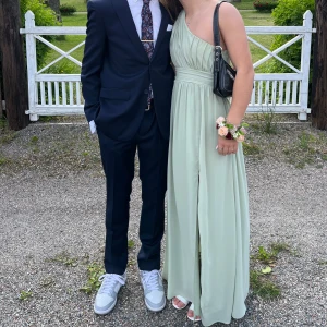 Ljusgrön långklänning oneshoulder - Säljer en elegant ljusgrön långklänning med oneshoulder och markerad midja. Klänningen har ett fint fall och plisserad överdel, perfekt för balen nu i nian eller studenten. Materialet känns mjukt och lätt, vilket gör den bekväm att bära hela kvällen, definitivt dansvänlig. Jag brukar ha storlek S och denna passar jättebra. Har bandstorlek 70/75 i bh om det hjälper. Pris kan diskuteras vid snabb affär 