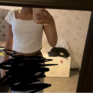 Vit croppad ribbad topp från Primark - Säljer en vit croppad topp från Primark med ribbad struktur och vågiga kanter vid ärmslut och nederkant. Toppen har korta ärmar och fyrkantig halsringning. Perfekt för sommaren! Och har aldrig använt den