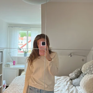 Beige sweatshirt med vingar från Hunkydory - Säljer en beige sweatshirt från Hunkydory Essentials med stora vingtryck på ryggen. Tröjan har rund hals och långa ärmar, perfekt för en avslappnad stil. Supermjuk insida och klassisk passform.