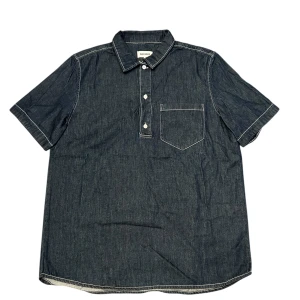 Mörkblå jeansskjorta från Weekday - Snygg mörkblå jeansskjorta från Weekday med korta ärmar och en bröstficka. Skjortan har knappar framtill och en klassisk krage. Perfekt för en avslappnad stil.