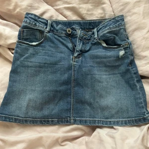 Blå jeanskjol från Zara - Säljer en klassisk blå jeanskjol från Zara med femficksmodell och knapp- samt dragkedjestängning framtill. Kjolen har en rak passform 