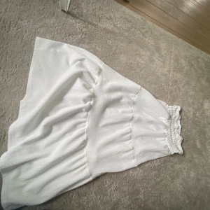 Vit volangkjol med resårmidja - Säljer en söt vit kjol med volang och bred resår i midjan. Kjolen har en luftig och flowy känsla, perfekt för varma dagar. Passar dig som gillar en enkel stil. Det är en lång kjol/maxikjol som passar ofta. Skriv för fler bilder 🥰
