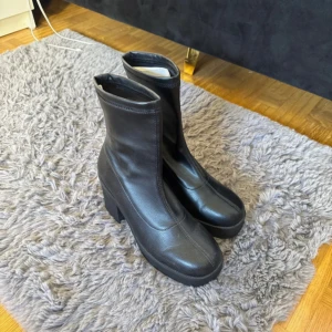 Svarta boots klackar  - Säljer ett par svarta boots i faux skinn med hög klack och platåsula. Klacken ungefär 7cm, storlek 38, från märket Attitude. Mary Jane/hoove design. 