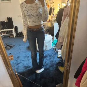 Vit virkad croppad tröja med snörning i ryggen - Superfin vit virkad croppad tröja från Pull and Bear med lång ärm och snygg snörning i ryggen. Perfekt för att lyfta en outfit med sin unika design och öppna rygg. Tröjan har ett vackert mönster och sitter tajt över kroppen.