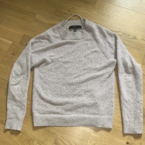 Lila stickad tröja från Vero Moda - Mysig beige stickad tröja från Vero Moda. Tröjan har rund halsringning, långa ärmar och ribbade muddar vid ärmslut och nederkant.