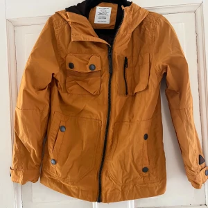 NEXT Senapsgul Barn jacka stk 146  - En oanvänd typ vindjacka med luva. Aldrig använd eller tvättad. Som ny.