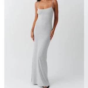 Ljusgrå långklänning med smala axelband - Säljer en stilren ljusgrå långklänning med smala axelband och figurnära passform. Klänningen har en enkel och tidlös design, perfekt för dig som gillar minimalistisk stil. Materialet är mjukt och stretchigt för extra komfort.