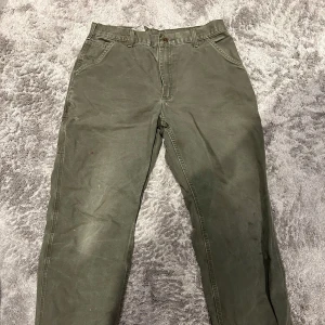 Gröna cargopants från Carhartt - Säljer ett par gröna cargopants från Carhartt med flera praktiska fickor och klassisk logopatch bak. Byxorna har normal passform och raka ben, perfekta för en avslappnad stil.