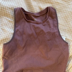 Ribbad träningstopp H&M - Säljer en ribbad croppad träningstopp från H&M. Färgen är brun/rosa. 