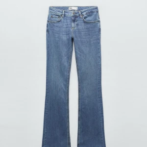 Blå bootcut jeans från Zara - Säljer ett par klassiska blå bootcut jeans från Zara med fem fickor och dragkedja med knapp. Jeansen har en normal passform upptill och utsvängda ben. Perfekta till sneakers eller boots.