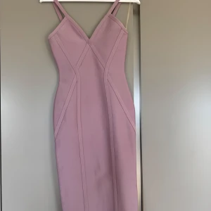 Ljuslila tight klänning från Girlcode - Säljer en ljuslila tight klänning från Girlcode med smala axelband och markerade sömmar. Klänningen har en slits bak och dragkedja i ryggen. Perfekt för dig som gillar en figurnära passform och stilren design.
