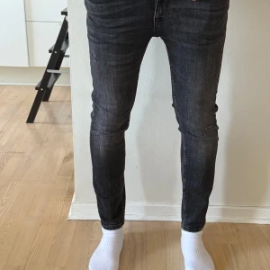 Svarta skinny jeans - Säljer ett par svarta skinny jeans med lätt slitning och klassisk femficksdesign. Jeansen har smal passform och normal midja, perfekta till vardagsstilen. Materialet är stretchigt för extra komfort. Dm för frågor!
