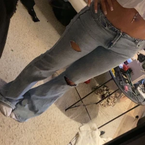 Ljusblå lågmidjade bootcut jeans med slitningar - Säljer ett par ljusblå lågmidjade bootcut jeans no waist