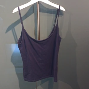 Mörkblå linnetopp från Gina Tricot - En enkel och stilren mörkblå linnetopp från Gina Tricot med tunna axelband. Perfekt att matcha med jeans eller kjol för en avslappnad look. Tillverkad i mjuk bomull för extra komfort.