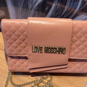 Rosa quiltad axelväska från Love Moschino - Säljer en snygg rosa axelväska från Love Moschino med quiltat mönster och guldfärgad kedja. Väskan har användts mycket tidigare men inte varit min stil på det senaste.⭐️💕