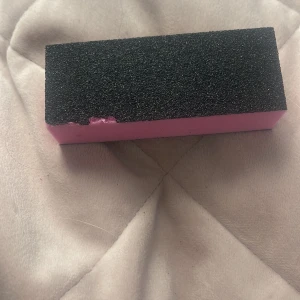 Svart och rosa nagelfilblock - Ett rektangulärt nagelfilblock med svart slipyta och rosa skumkärna. Perfekt för att fila och polera naglarna för en jämn och fin yta. Enkel att hålla i och använda tack vare sin fyrkantiga form.