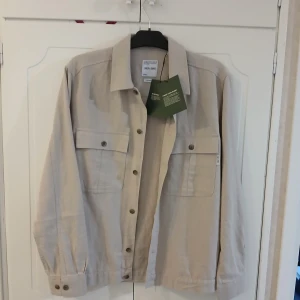 Beige overshirt från Only & Sons - Helt ny, Snygg beige overshirt från Only & Sons i en luftig linnemix. Jackan har klassisk krage, knäppning framtill och två stora bröstfickor med lock. Perfekt för lager-på-lager och en clean look. Storlek S men passar s/m