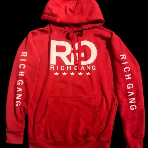 Rich Gang Apparel Hoodie - Snygg sällsynt röd hoodie från Rich Gang med stort vitt tryck på bröstet och text på båda ärmarna. Tröjan har huva med snörning och en stor magficka. Perfekt för dig som gillar streetwear och vill sticka ut med en bold look.
