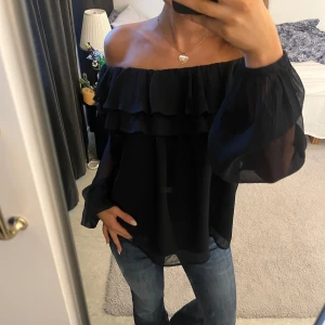 Svart offshoulder blus med volanger - Säljer en svart offshoulder blus med volanger, samt avslappnad passform😋