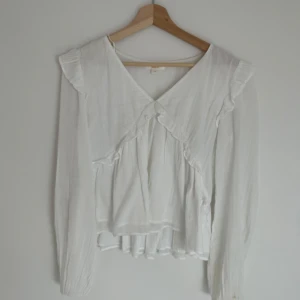 Vit blus ifrån Gina Tricot - Den vit långarmad blus men lite volanger i storlek 170