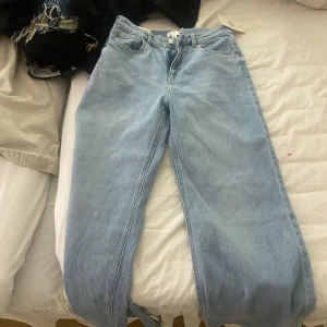 Ljusblå wide jeans från H&M, strl 38 - Säljer ett par ljusblå jeans från H&M i storlek 38. De har en relaxed wide fit med raka ben och klassisk femficksdesign. Jeansen är tillverkade i bomull och har en snygg, enkel look som passar till allt. Perfekta för dig som gillar en chill och trendig stil. Har fortfarande kvar lapparna helt oanvända 
