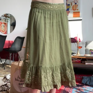 Olivgrön långkjol med paljetter - Halvlång kjol med guldpaljetter och volanger. Jag har själv sytt på två band för att kunna spänna åt den lite (men de är nog ganska lätta att själv få bort om man vill) 