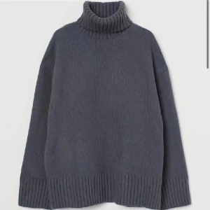 Mörkgrå stickad polotröja - Mysig mörkgrå stickad polotröja med oversized passform och bred ribbstickad krage, ärmslut och nederkant. Perfekt för lager-på-lager och chill höst- eller vinterstil. Enkel att matcha med jeans eller kjol för en avslappnad vibe.