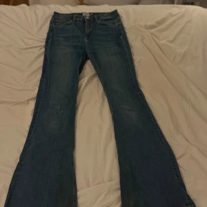 Blå Snake Flare jeans från 157 - Snygga blå jeans från 157 i modellen Snake Flare. De har klassisk femficksdesign, flare-ben och coola kontrastsömmar. Perfekta för dig som gillar retrovibbar och vill ha ett par jeans med lite extra attityd.