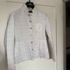 J.Lindeberg tunn dunjacka  - Jackan är i nyskick då den aldrig är använd, däremot är det smink över ena axeln, som skedde när jackan låg i en väska med annan packning. Har ej försökt tvätta jackan. Nypris 3600kr. Möts på Ekerö annars står köparen för frakt.