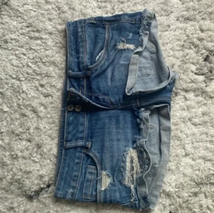Blå jeansshorts med slitningar - Snygga low waist mini jeansshorts i strl 34, midja:38. Kommer fler unika jeansshorts/kjolar så följ!!