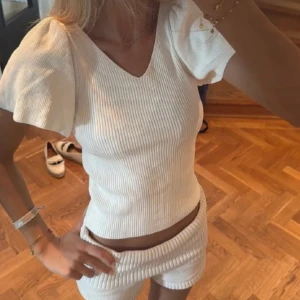 Vit ribbad topp med puffärm - Superfin vit ribbad topp med v-ringning och korta puffärmar..