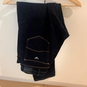 Mörkblå Armani Jeans J53 Regular - Snygga mörkblå jeans från Armani Jeans, modell J53 Regular. Klassisk femficksdesign med kontrastsydda sömmar och metallfärgad logga på bakfickan. Jeansen är tillverkade i slitstarkt denim och har en normal passform som funkar till många stilar.