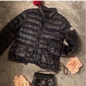 Svart dunjacka från Moncler - Snygg svart dunjacka från Moncler, perfekt till hösten. Jackan har dragkedja framtill, två fickor. (ÄKTA). OBS dragkedjan är trasig längst ner, jag har ej fixat därav att jag ändå vill sälja, går att laga ( därav billigt pris) ❤️hör av dig för mer frågor